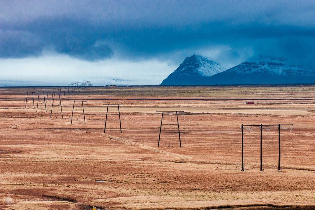 Sequência de postes eléctricos numa planície da costa sul