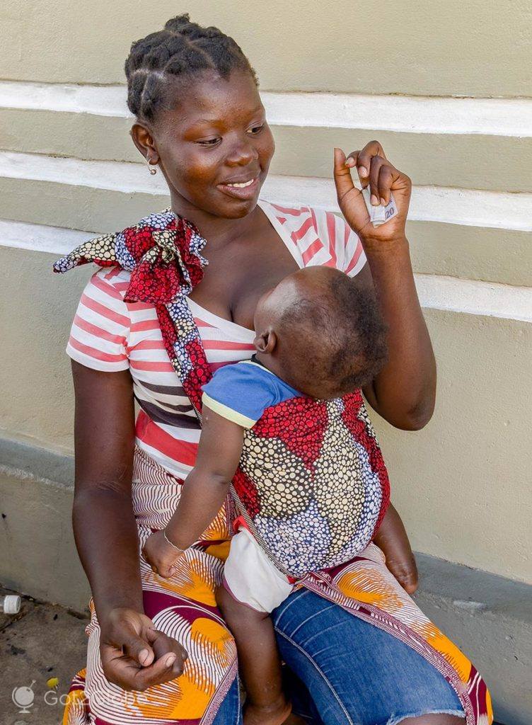 Vendedora de jambalão segura o seu bebé numa rua de Inhambane