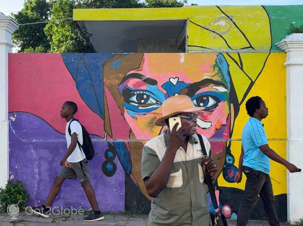 Transeuntes passam por um mural da cidade de Inhambane