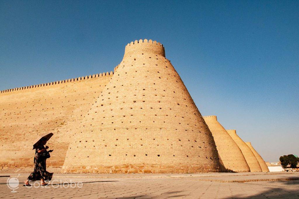 Mulher passa em frente à fortaleza Ark de Bukhara.